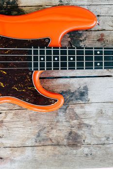 orange electric bass guitar on wood background
