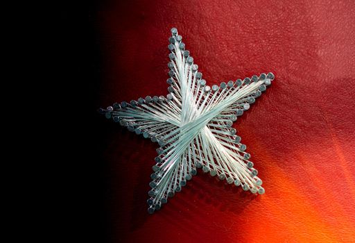 A star made from steel nails and string on red background