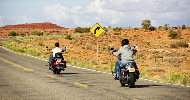 Bikers Riding Down the Arizona Highway in Summer Day. Biking Photo Theme. Transportation Collection. 
