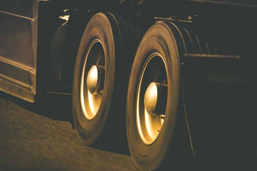 Spinning Semi Truck Wheels Closeup Photo. Browny Color Grading. Trucking and Transportation Theme.