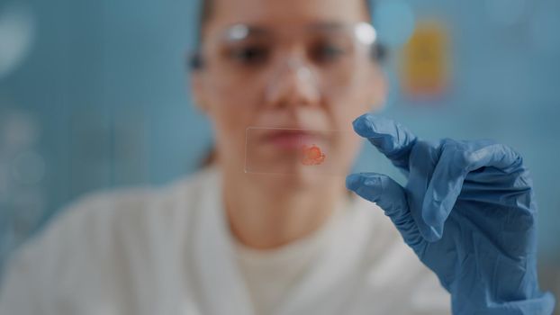 Woman biologist analyzing blood sample on glass tray