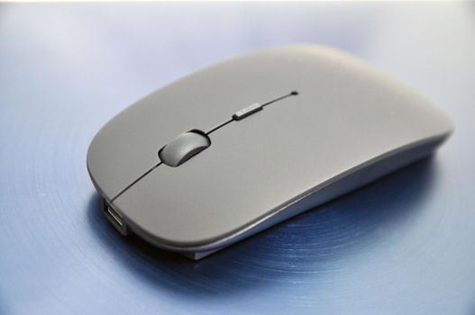 Wireless rechargeable computer mouse on a blue background.