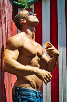 Muscular Man Outdoor Applying Suntan Oil to Skin