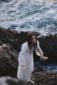 woman outdoors in white dress near the ocean stones travel. High quality photo