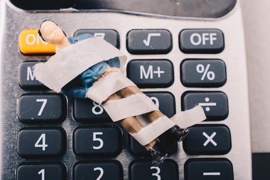 Tiny figurine of man model  wrapped in bandages on calculator