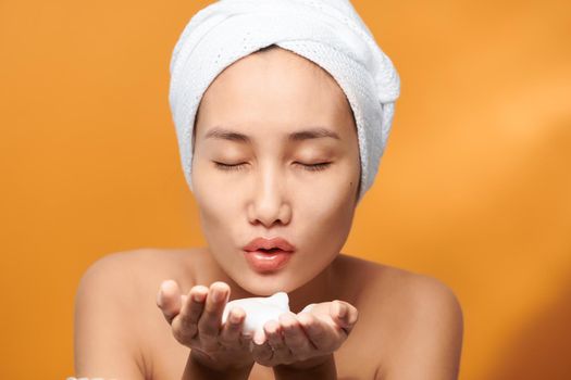 Happy young beautiful Asian blowing foaming cleanser on her hand. Spa concept.