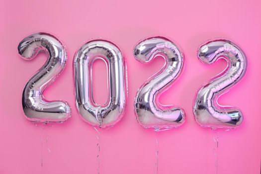 Multicolored foil balloons numeral 2022 on pink background
