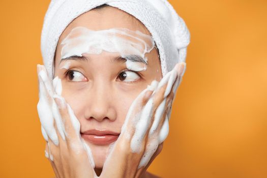 Close up of beautiful young Asian woman with cleansing foam for skin care.
