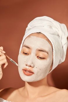 Attractive woman applying clay mask on her face.