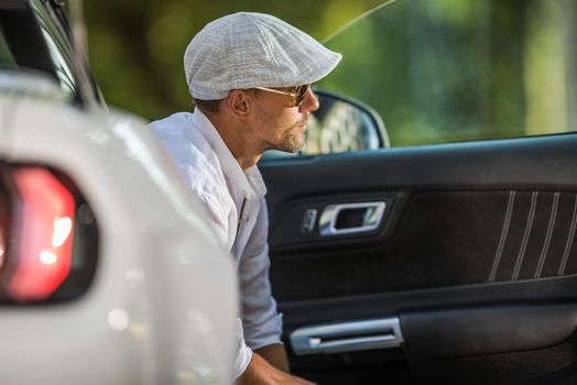 Young Caucasian Men Wearing Stylish Beret and Sunglasses Seating Inside His Modern Convertible Car and Enjoying the Moment.