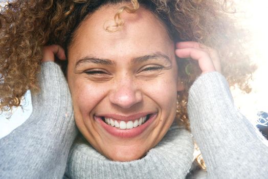 Close up cheerful young african american woman laughing with hands in hair