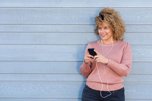 smiling woman listening to music with headphones and mobile phone