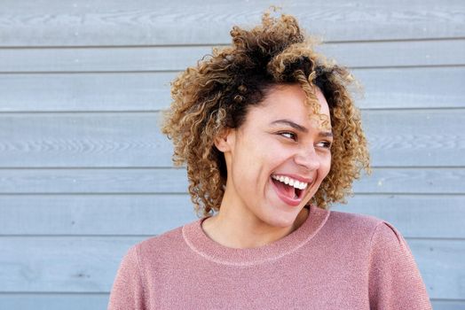 horizontal portrait beautiful african american woman laughing against gray wall