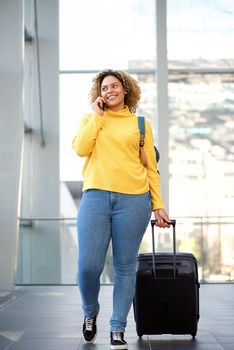 Full body african american travel woman walking and talking with mobile phone at station