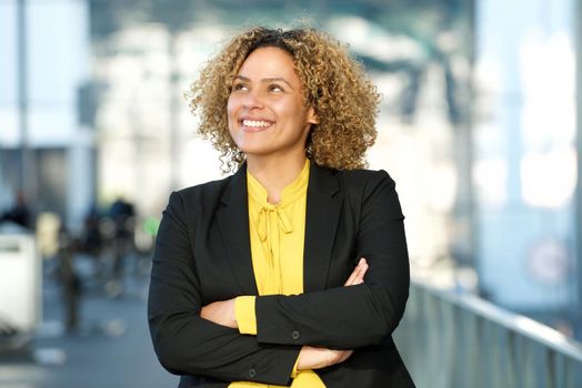 smiling businesswoman with arms crossed and looking up