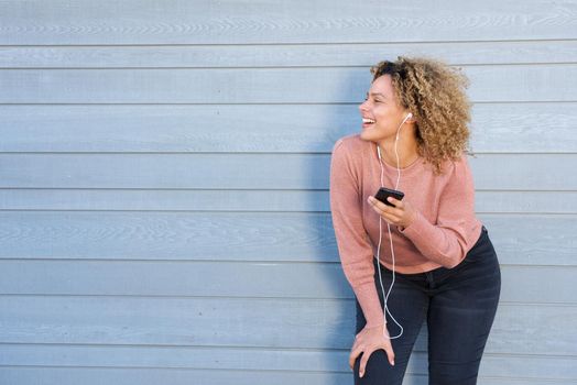 happy african american woman listening to music with earphones and cellphone