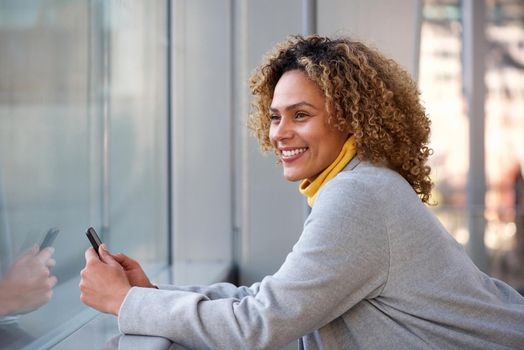 Side of beautiful african american woman smiling with mobile phone 