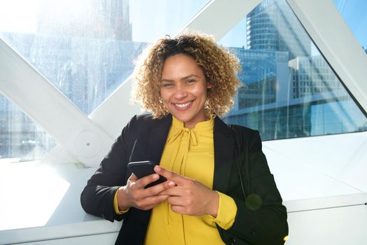 Close up happy african american business woman in the city with cellphone
