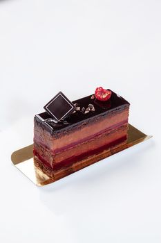 Sponge cake slice with cocoa mousse, jellied raspberry jam topped with chocolate icing