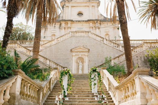 Open wedding semi-arch decorated with vines and roses stands on stone steps