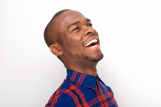Close up side of happy young black man laughing against white background