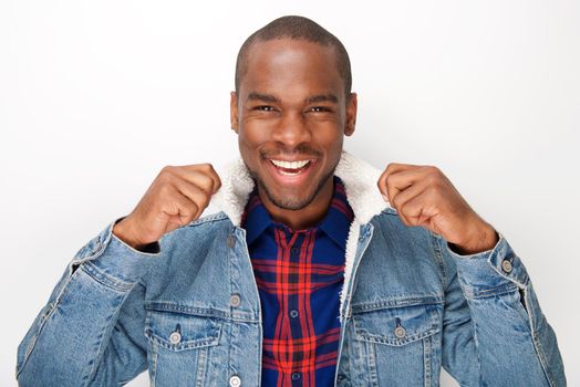 Close up portrait of cool young black male fashion model smiling with denim jacket against white wall