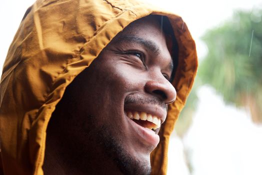 Close up happy black man with raincoat outside in rain
