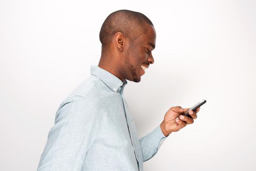 Profile of happy young black man looking at cellphone by white background
