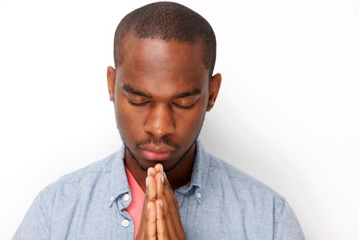 Close up young black man praying with hands clasp together