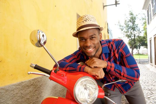 happy african american man leaning on motor scooter 