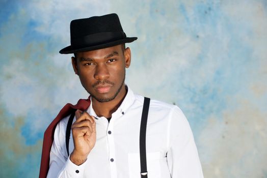 Close up cool young african american man posing with hat against wall