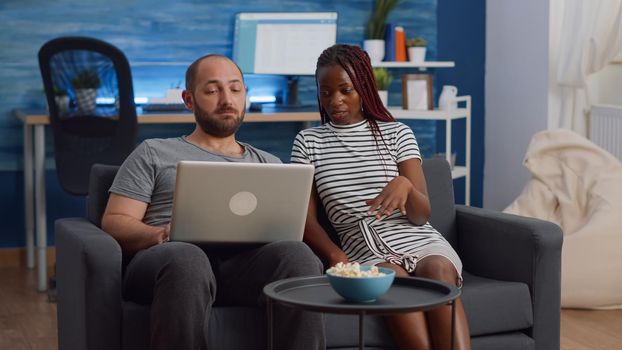Young interracial couple looking at modern laptop