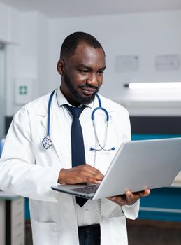 African american practitioner doctor holding laptop checking sickness symptoms