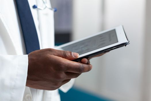 Closeup of african american doctor analyzing sickness expertise using tablet