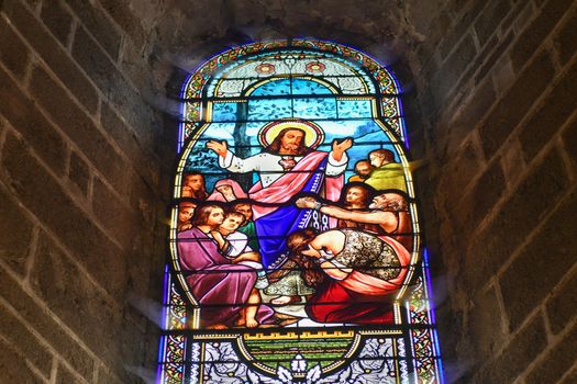 SAINT JUNIEN, FRANCE - DECEMBER 30, 2020: Stained glass windows in the church with Jesus Christ and people asking for healing