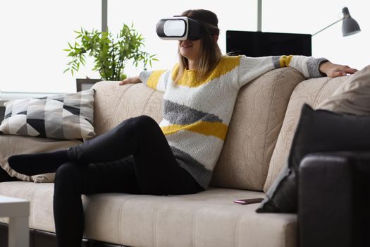 Female sit on couch wear vr glasses modern device at home and enjoy spare time