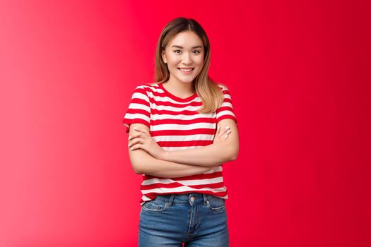 Friendly happy enthusiastic cute blond asian girl look camera smiling toothy white grin, cross arms chest self-soothing relaxed pose trying act normal talking stranger cafe queue, red background