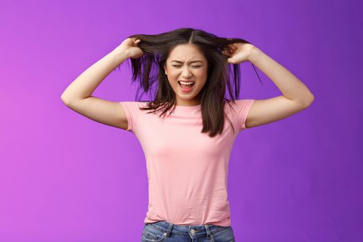 Upset distressed asian brunette girl frowning screaming, pull out hair fed up poor haircare, disappointment weak strands, stand purple background annoyed, pissed complain hairsalon