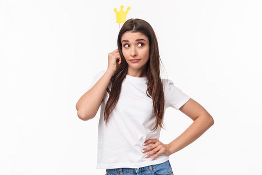 Entertainment, fun and holidays concept. Portrait of sassy and classy good-looking girl in t-shirt, holding carnaval stick with crown, acting like queen or super star, standing white background