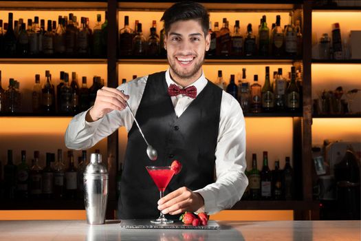 Young barman serving a cocktail at night club.