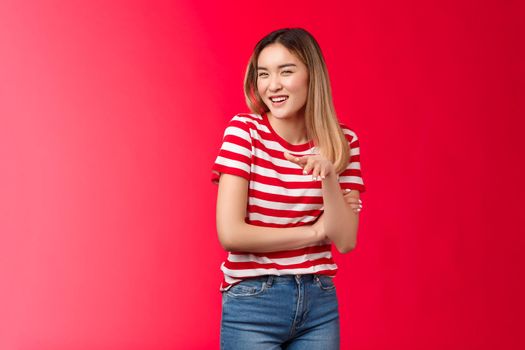 Glamour cute silly asian blond girl giggling girlfriends, smiling white toothy grin look camera waving palm, done nails, show nailpolish laughing gossiping friends have fun, stand red background