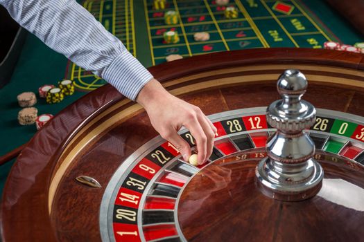 Roulette wheel and croupier hand with white ball in casino