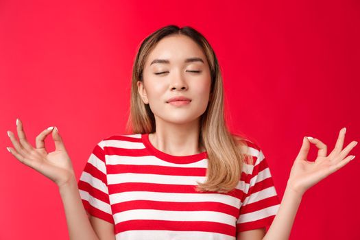 Girl feeling zen. Cute asian girl meditating unite with nature, close eyes breathing deep hold hands raised lotus nirvana pose, practice yoga, inhale air, release stress, calm-down red background
