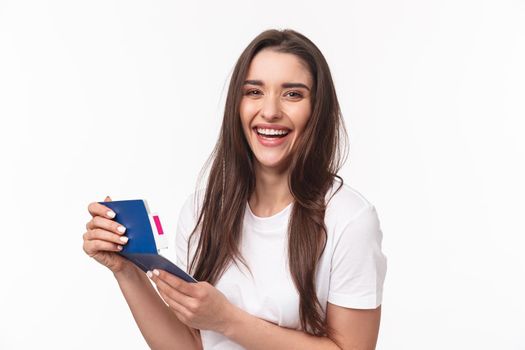 Travelling, holidays, summer concept. Close-up portrait of happy, charismatic pretty woman laughing, looking at her visa in passport with plane ticket, smiling joyful camera, ready for journey
