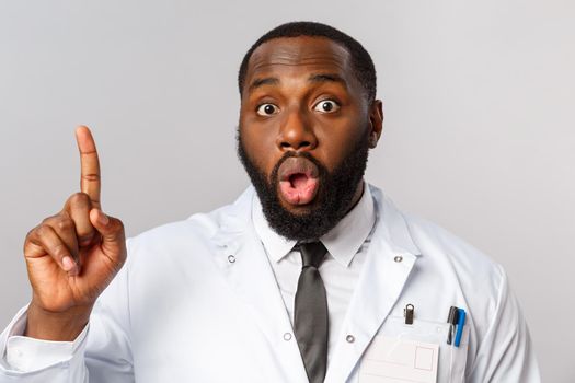 Healthcare, medicine and hospital treatment concept. Close-up of handsome funny african-american doctor talking about safety during covid19 outbreak, show finger number one rule safe-distancing
