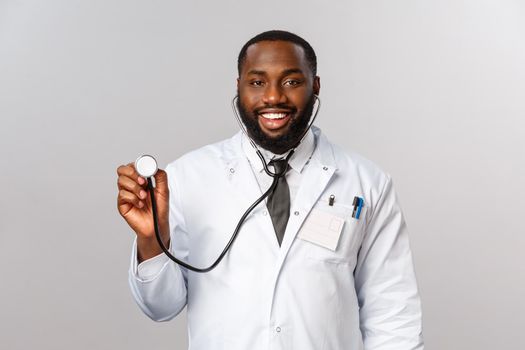 Covid19, hospital check-up and healthcare concept. Handsome african-american doctor, physician came to patient with stethoscope treating coronavirus symptoms with lungs, breathing capacity