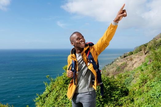 african american male hiker with backpack pointing finger outdoors 
