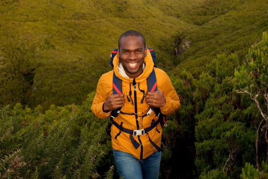happy young black man hiking in nature with backpack