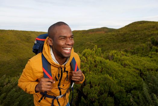 happy african american male backpacker walking in nature 