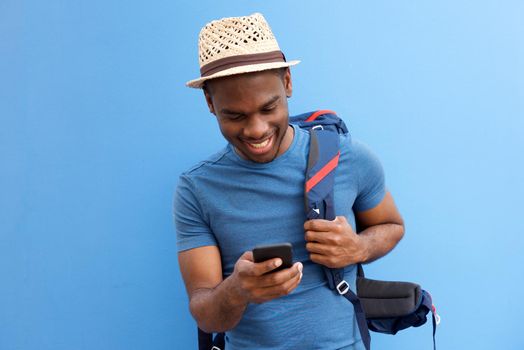 cool young african american guy with bag and cellphone against blue background